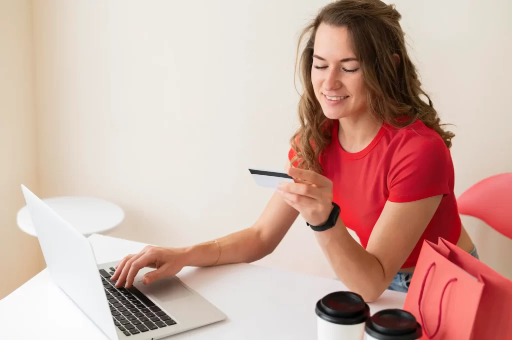 Emprendedora sonriente gestionando pedidos desde smartphone y laptop, éxito de tienda en línea creada con WooCommerce o Shopify